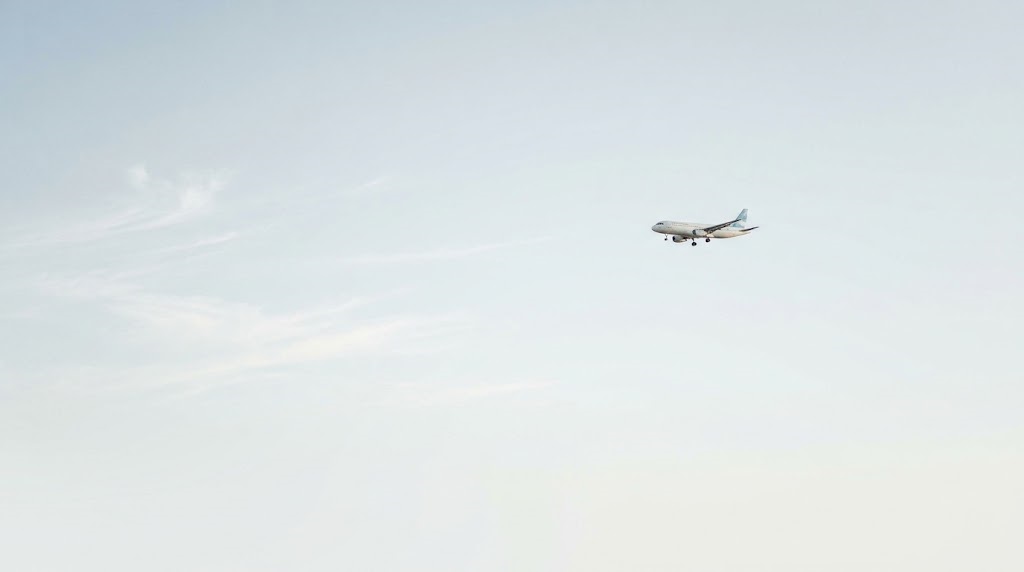 Small passenger plane flying across a pale blue sky
